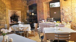 A restaurant with brick walls, a fireplace, and tables set for dining. - Hotel Corner (Tbilisi)