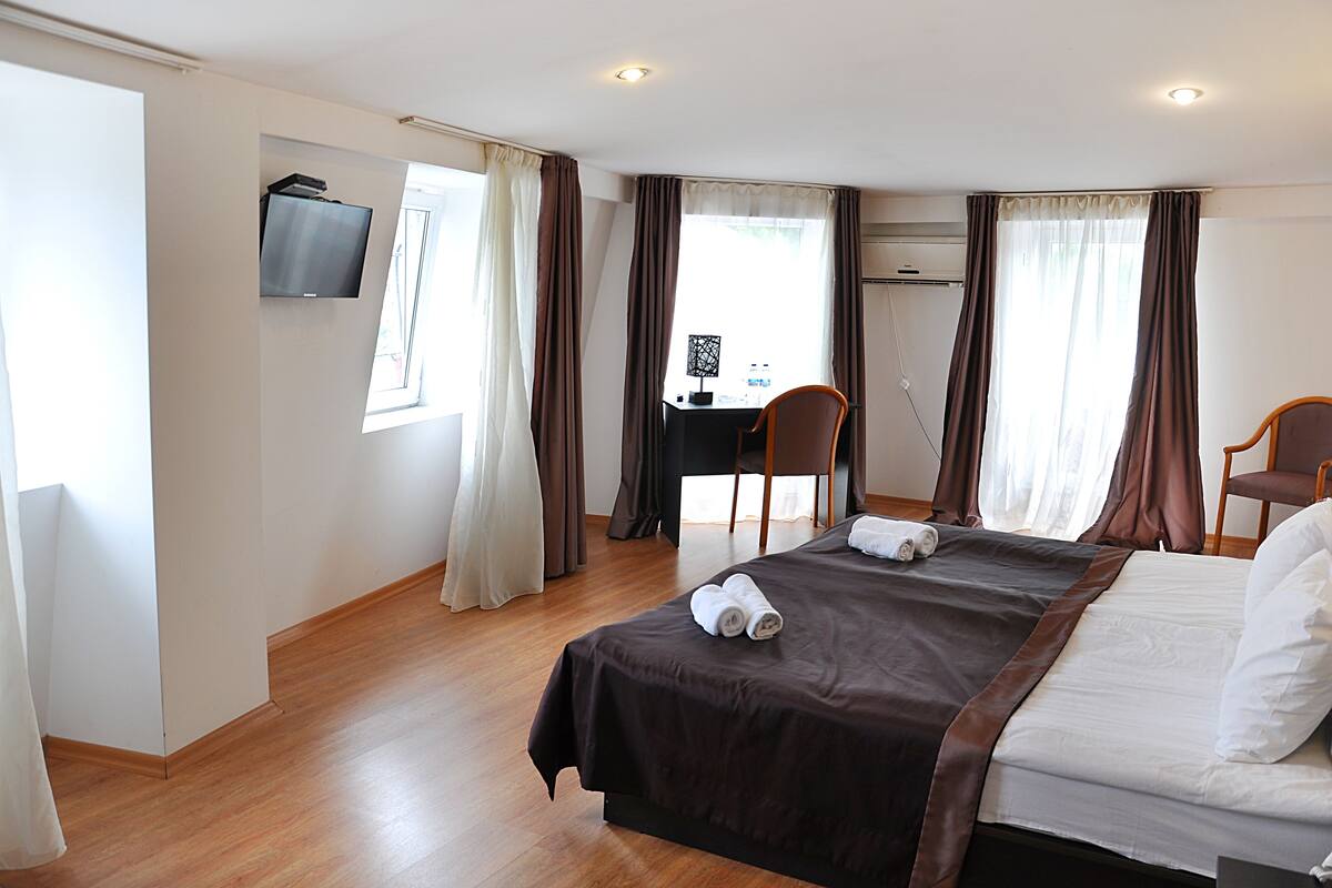 A hotel room with a bed, a desk, a chair, and a television.