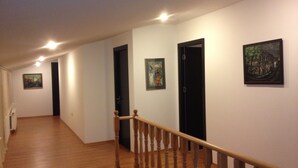 A hallway with wooden flooring, a wooden staircase with a handrail, and doors leading to rooms. - Hotel Corner (Tbilisi)