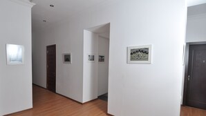 A hallway with wooden flooring, white walls, and framed pictures. - Hotel Corner (Tbilisi)