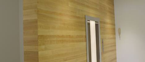 Un interior moderno con un panel de madera en la pared y una puerta metálica.