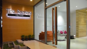 Hotel Scenery City met een modern interieur, glazen deuren en een zithoek met oranje stoelen en een witte bank.