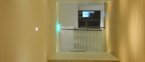 A modern interior with a wooden floor, a glass partition, and a television mounted on the wall.