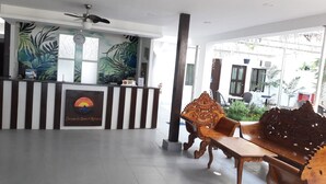 A reception area with a reception desk, a clock, and a large window with tropical plant murals. - Deparis Beach Resort (Boracay Island)