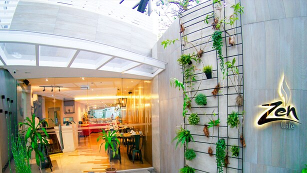 A Zen Cafe with a modern interior, a wall-mounted plant display, and a welcoming entrance. - Zerenity Hotel & Suites (Cebu City)