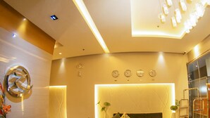 A modern living room with a sofa, two armchairs, a coffee table, and a decorative wall with clocks. - Zerenity Hotel & Suites (Cebu City)