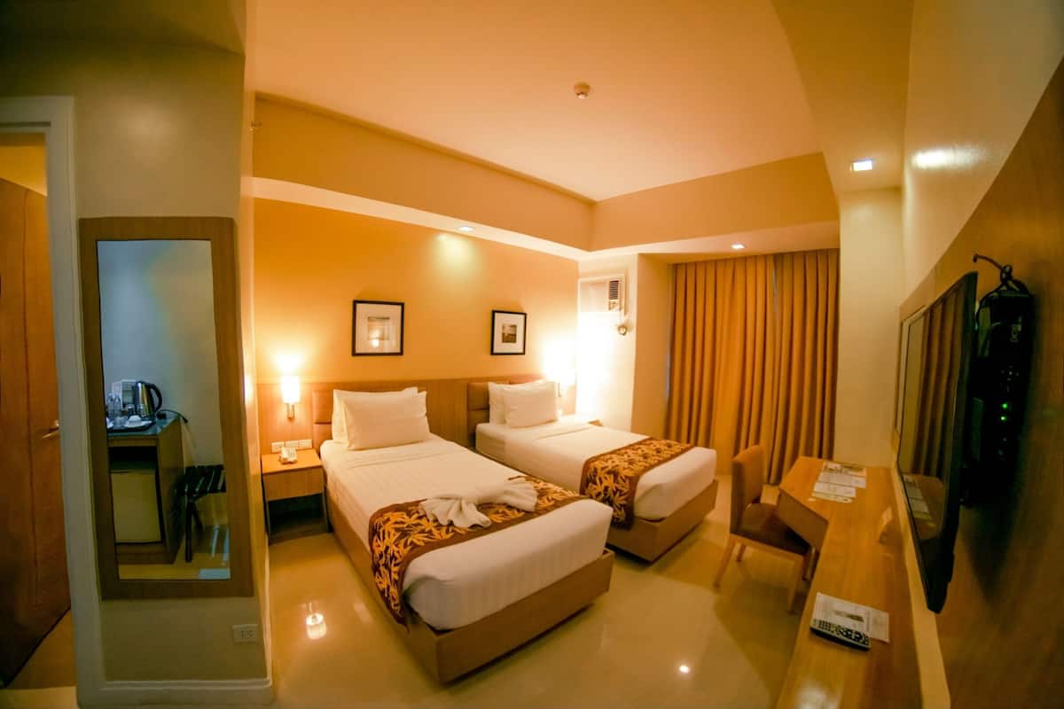 A hotel room with two beds, a desk, a chair, a TV, and a mirror.