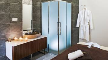 Un baño moderno con un tocador de madera, un armario de vidrio, un lavabo con cuenca de piedra y una toalla en la cama.
