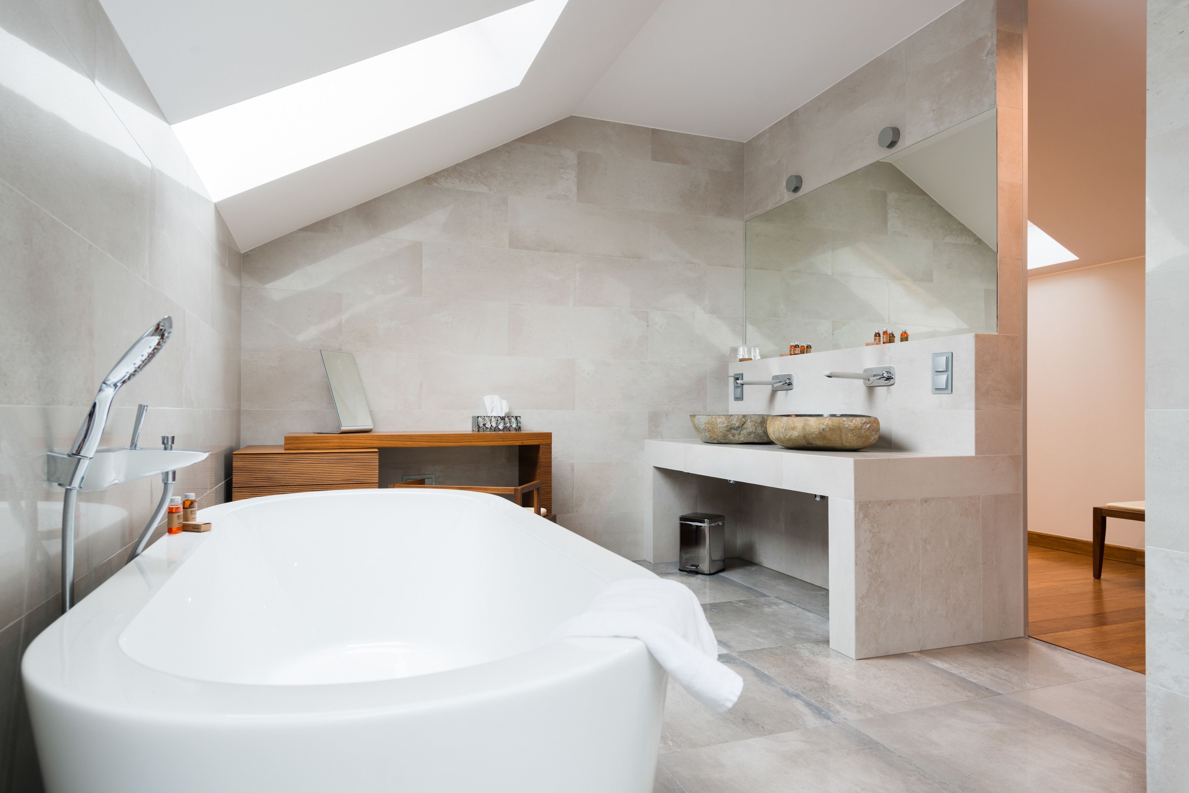 A modern bathroom with a freestanding bathtub, a wooden vanity, and a large mirror.