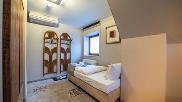 Een slaapkamer met een bed, een raam, een airconditioner en een houten kledingkast.