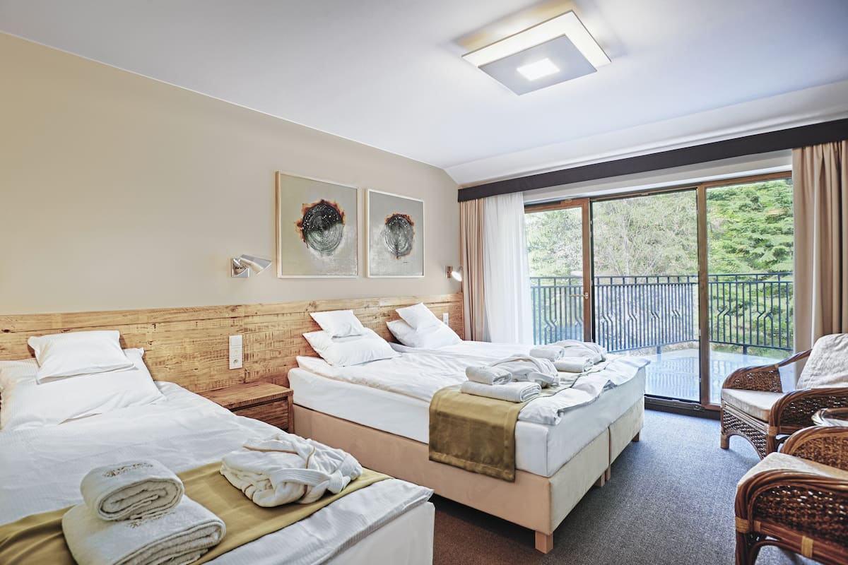 Ein Hotelzimmer mit zwei Betten, einem Balkon, Korbmöbeln und Bildern an der Wand.