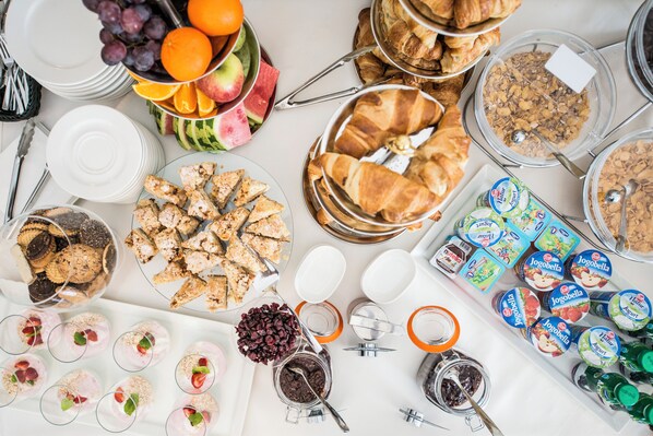 A buffet table with various food items including fruits, pastries, and dairy products.