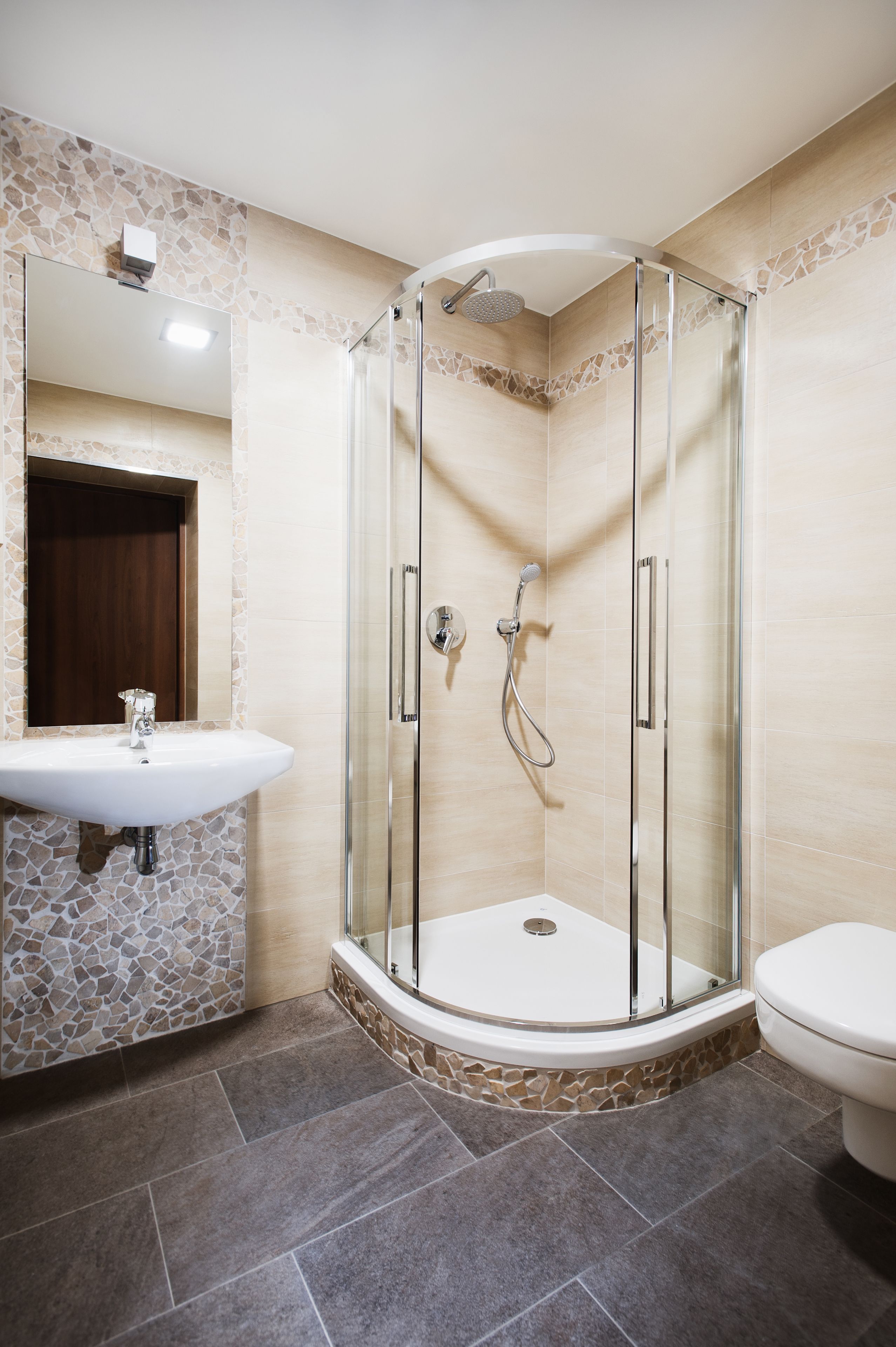 Une salle de bain moderne avec une douche à parois de verre, un lavabo sur colonne et des toilettes.