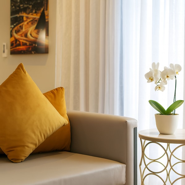 Una sala moderna con un sofá, una mesita redonda y una orquídea en maceta.