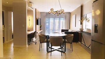 A modern dining area with a round table, four chairs, and a unique chandelier.