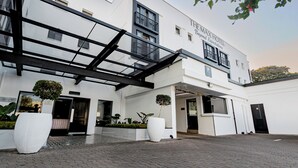 Ein modernes Hotel mit Glastür, überdachtem Außenbereich und einem Schild mit der Aufschrift "The Max Hotel Beyond Expectations".