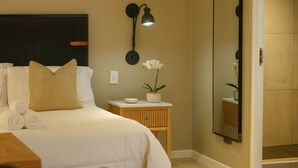Ein Hotelzimmer mit einem Bett, einem Nachttisch, einer Lampe und einem Spiegel.