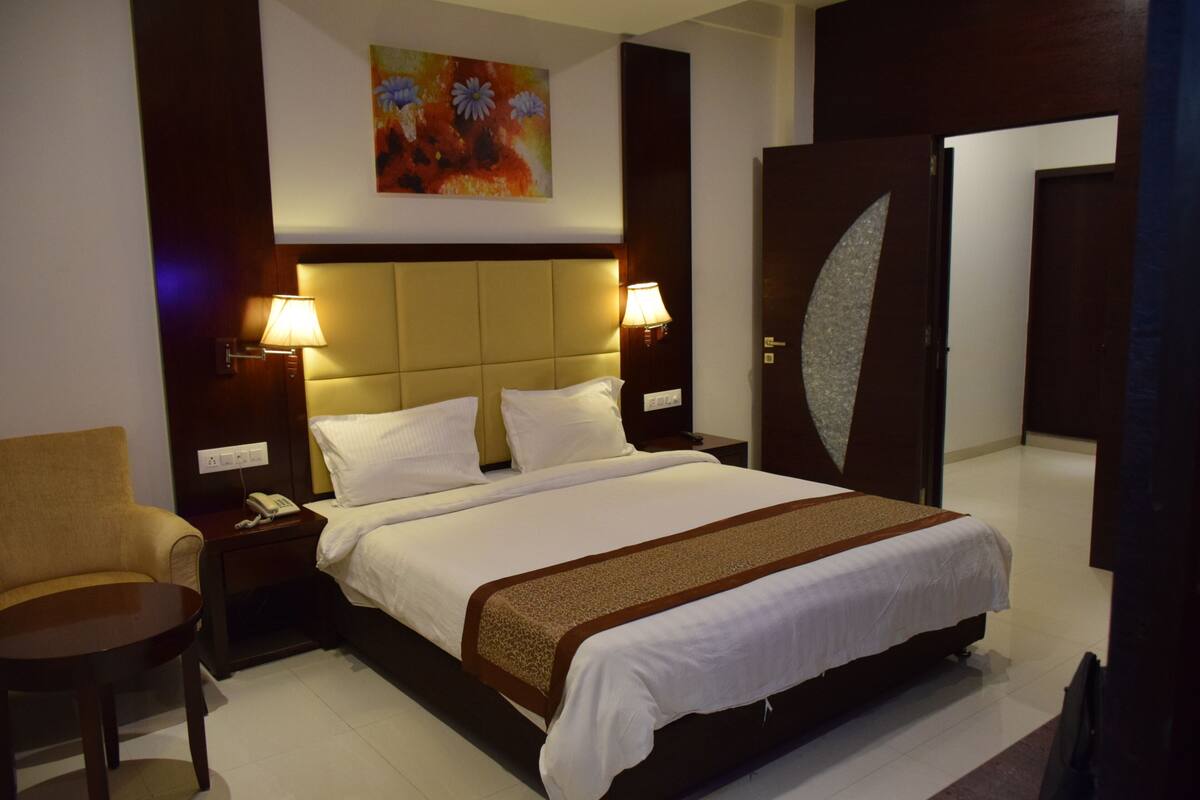 Une chambre d’hôtel avec un lit, deux lampes de chevet, une chaise, un tableau au mur et une porte au design original.