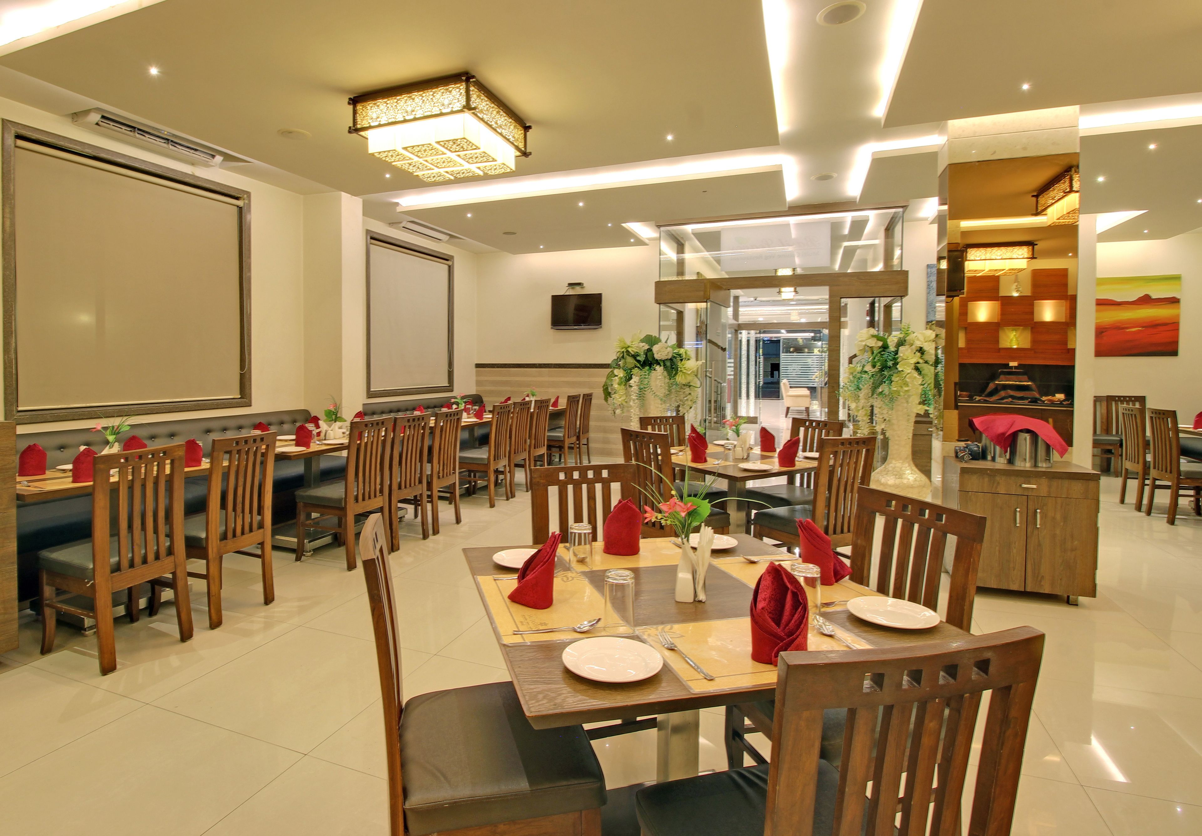 A spacious dining area with multiple tables and chairs, a large screen on the wall, and a television.