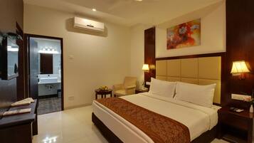 A hotel room with a large bed, a chair, a desk, a mirror, and a painting on the wall.