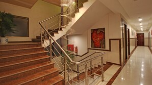 Un moderno vestíbulo de hotel con una escalera de mármol, un cuadro abstracto de gran tamaño y un suelo limpio y pulido.