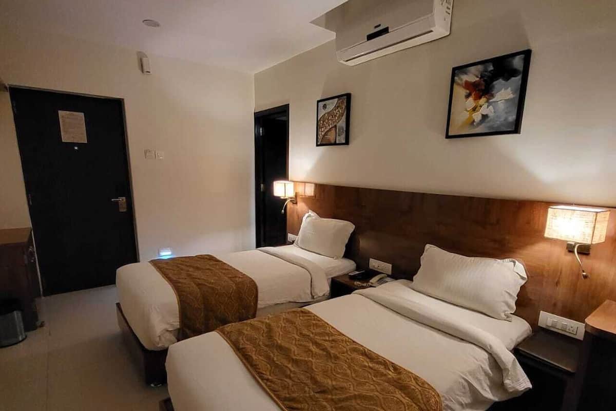 Une chambre d’hôtel avec deux lits, un ventilateur de plafond, un appareil de climatisation et un tableau au mur.
