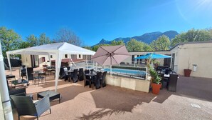 Un patio al aire libre con mesas y sillas, una piscina y una estructura tipo carpa.