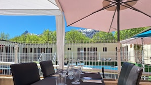 Una mesa de comedor con sillas, una piscina y vistas a la montaña.