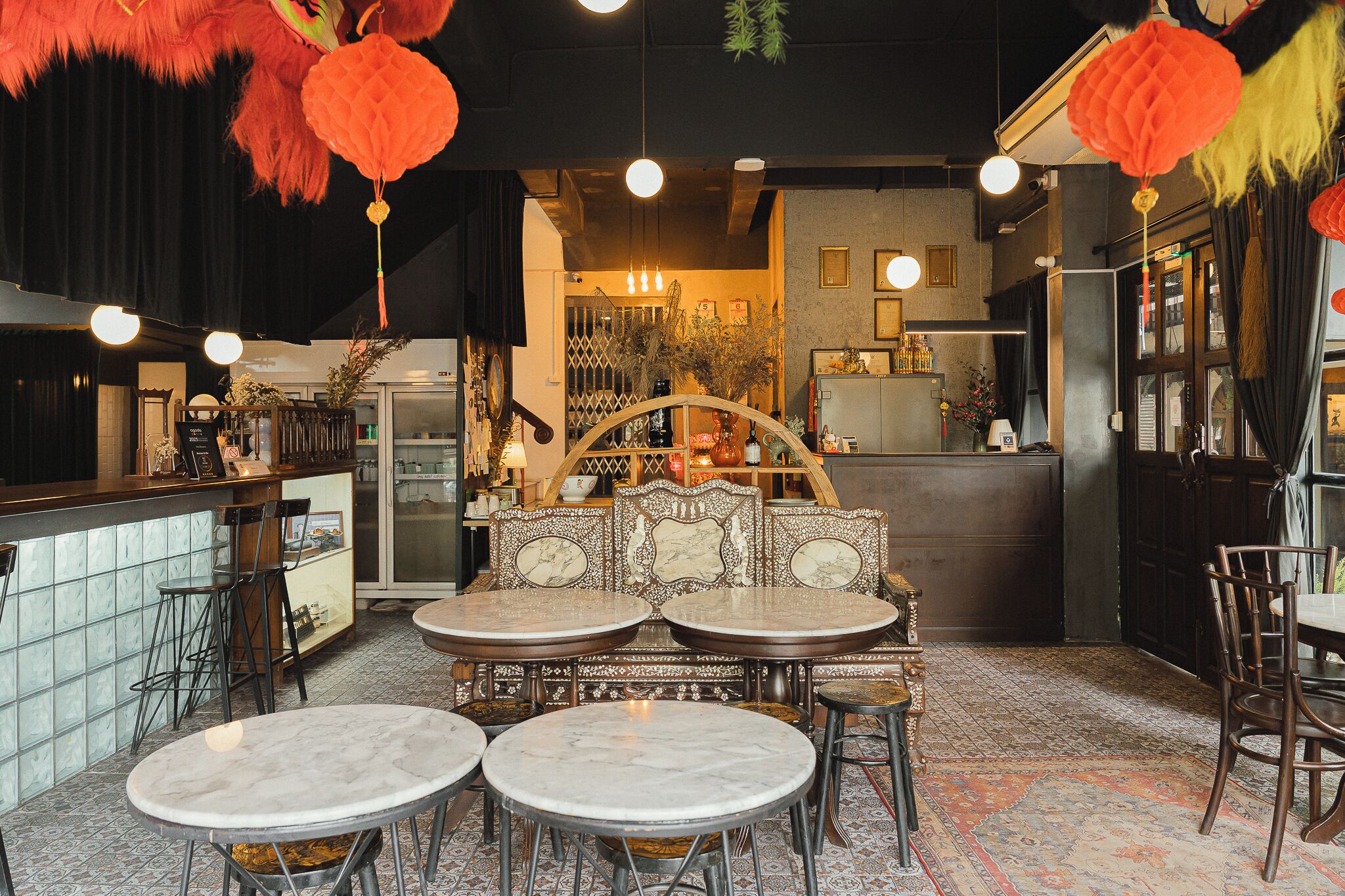 A restaurant interior with round marble tables, a bar area, and traditional decor.