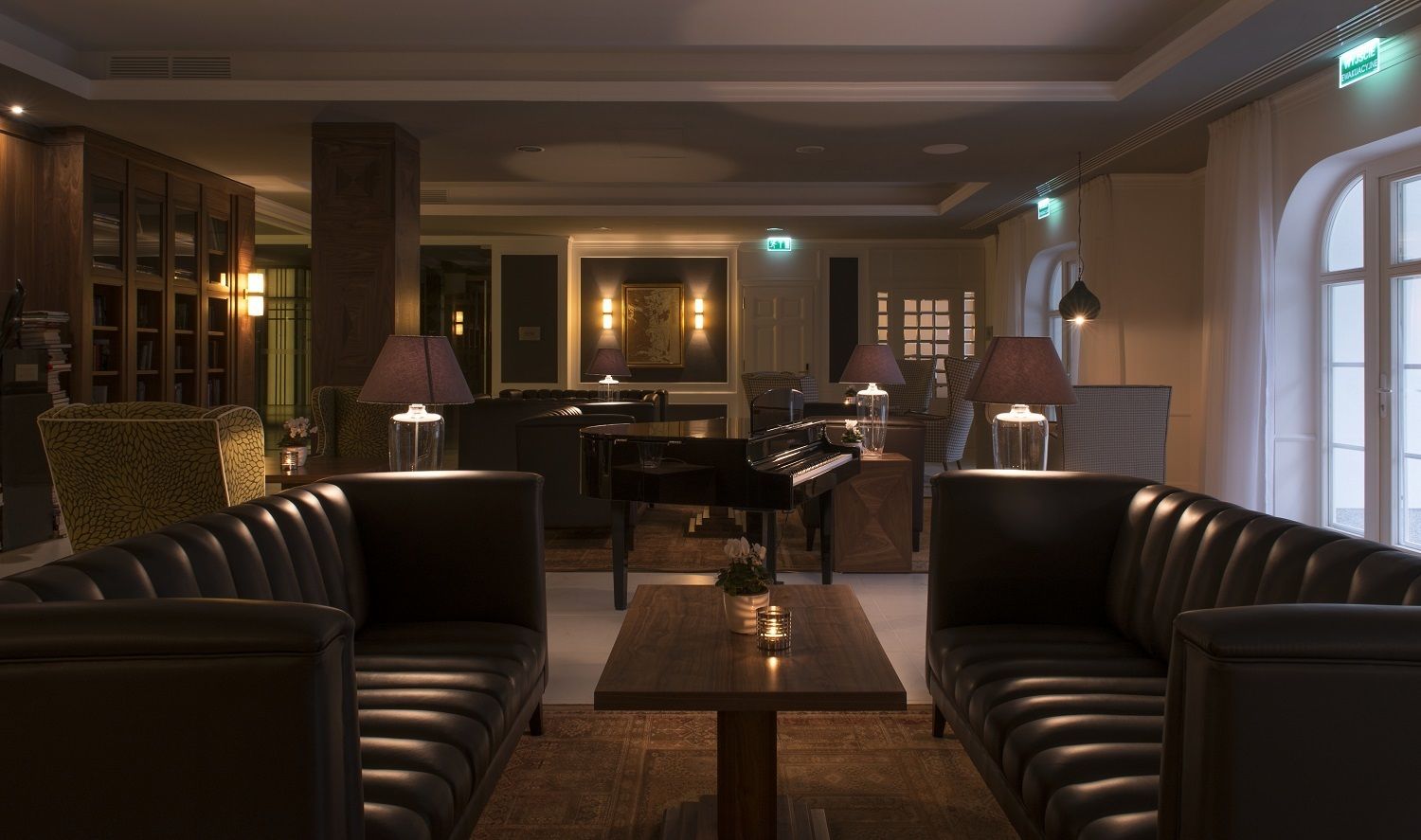 A modern lounge area with leather sofas, a piano, and a bar.
