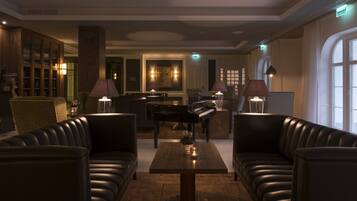 A modern lounge area with leather sofas, a piano, and a bar.