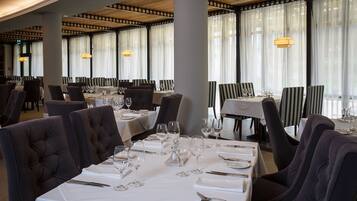 A restaurant with tables set for dining, featuring striped chairs and a modern ceiling design.