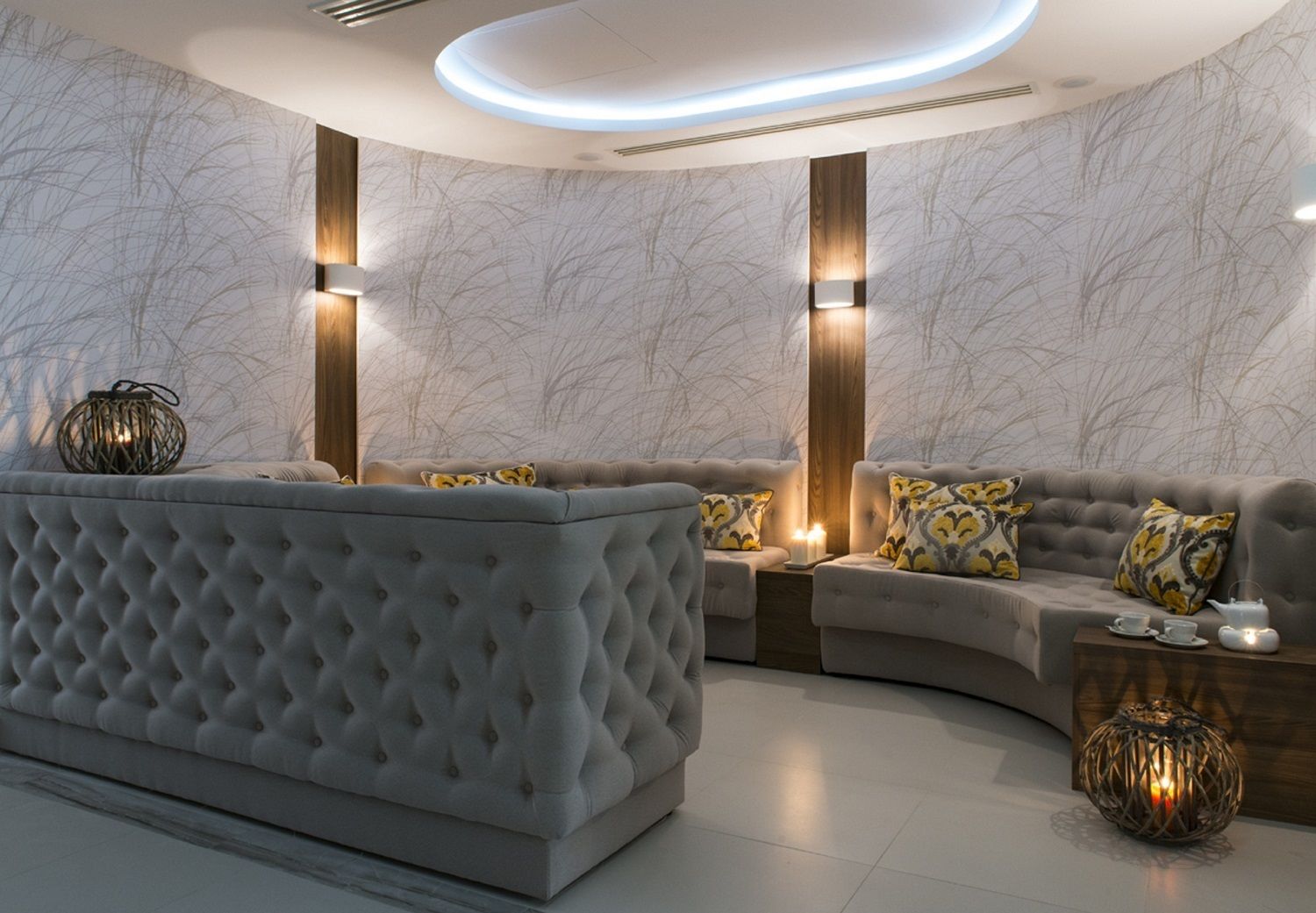 A modern living room with a tufted sofa, a curved coffee table, and decorative lighting.