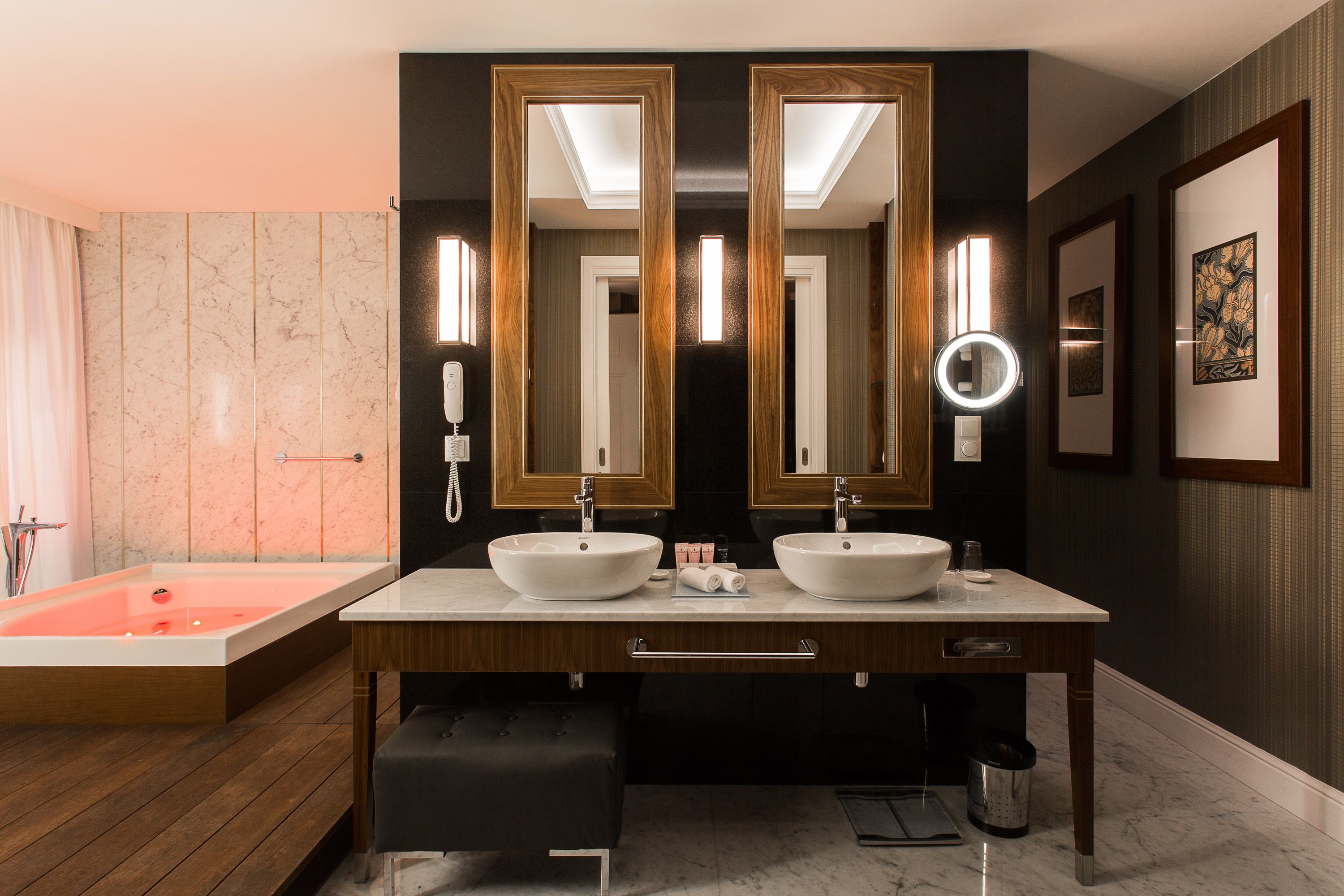 A modern bathroom with two sinks, a large bathtub, and a vanity with a mirror.