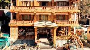 A two-story wooden building with a balcony, outdoor seating, and a car parked in front. - Whispering Inn by Vivaan (Manali)