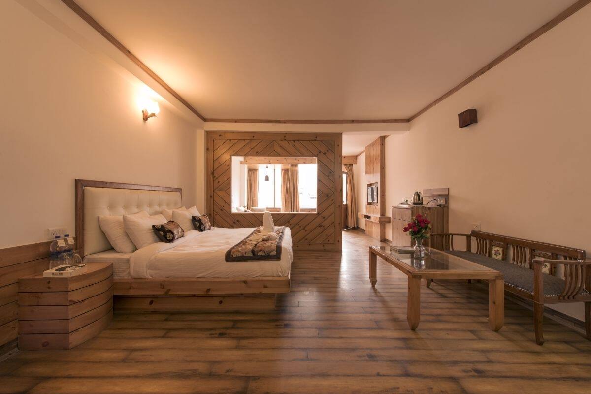 A bedroom with a wooden bed, a nightstand, a wooden table, and a bench.