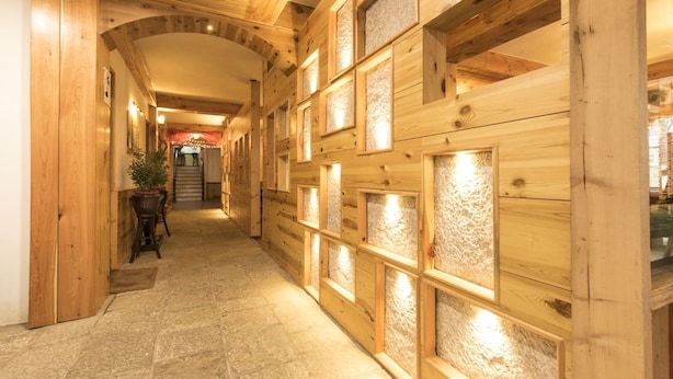 A wooden hallway with stone flooring and a staircase leading to a higher level. - Whispering Inn by Vivaan (Manali)