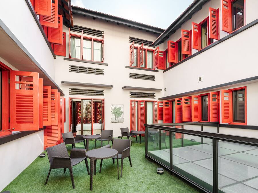A courtyard with red shutters, outdoor seating, and a glass railing.