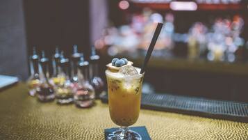 A cocktail with ice cubes and a straw in a glass, placed on a textured tablecloth.