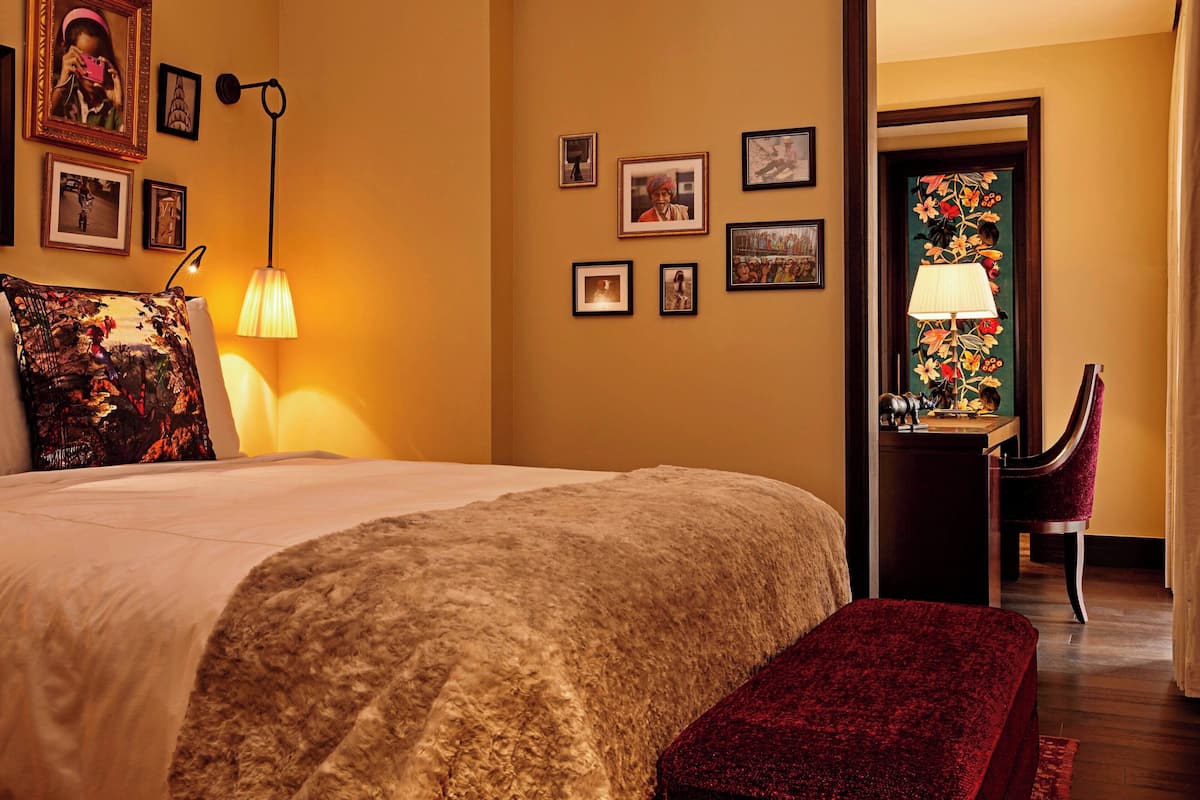 A hotel room with a large bed, a desk with a chair, and a door with a floral design.