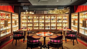 A bar area with multiple liquor cabinets and round tables with chairs. - The Vagabond Club, Singapore, a Tribute Portfolio Hotel (Singapore)