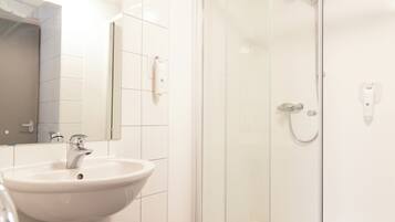 Un baño con lavamanos, espejo y cabina de ducha de vidrio.