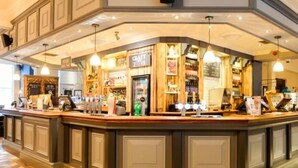 A bar area with a counter, bar stools, and a menu board.