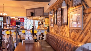 A restaurant interior with wooden walls, a bar area, and a seating section with a high backrest.