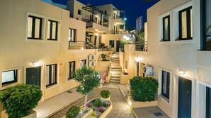 Un edificio moderno con varios balcones, una escalera central y plantas en macetas.