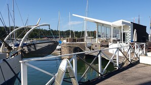 A marina with boats docked, a covered seating area, and a clear sky. - Segelfartyget Libelle (Oxelosund)