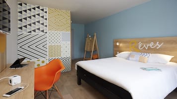 A hotel room with a bed, a desk with a laptop, and an orange chair.