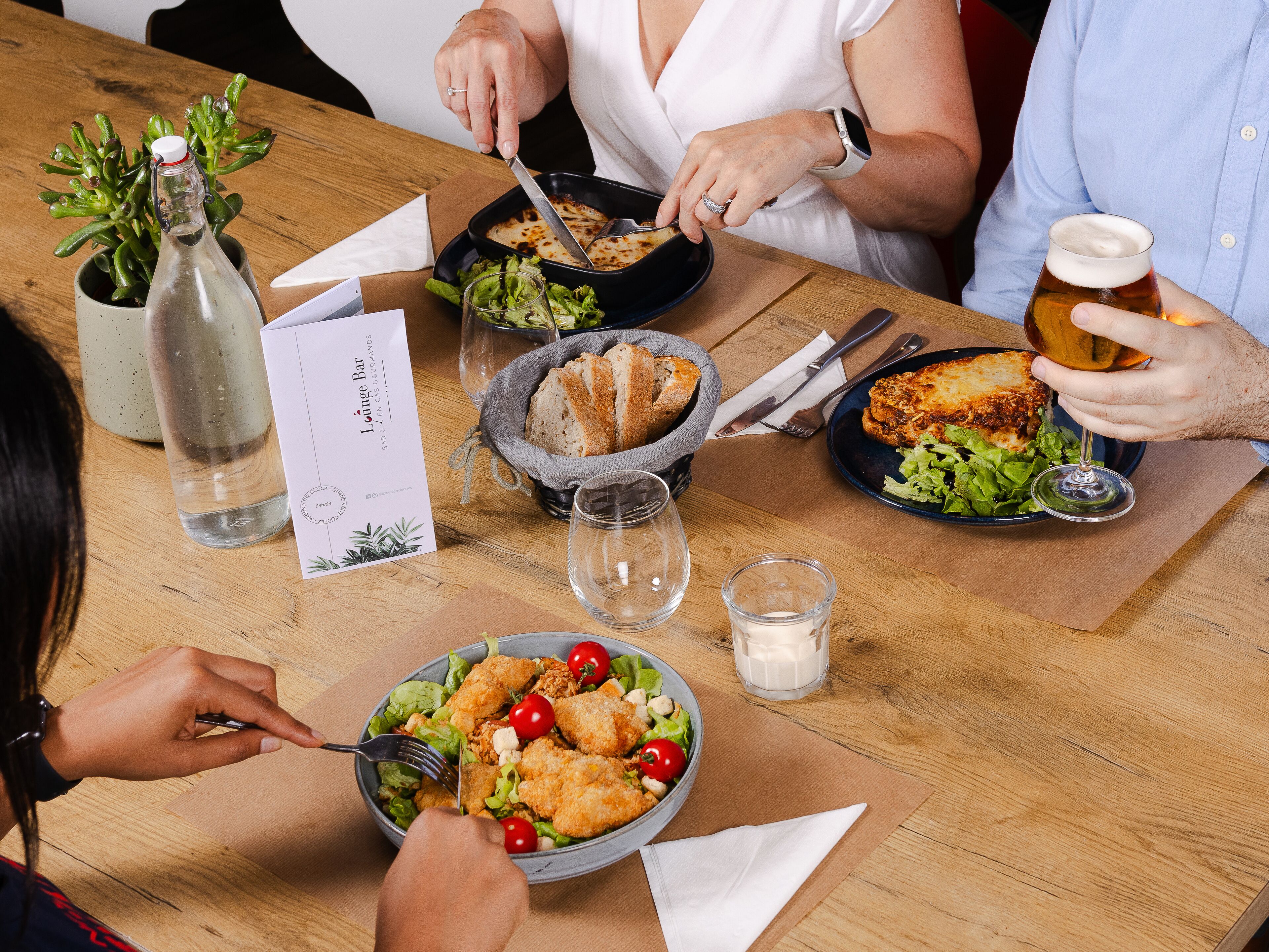Una mesa con varios platos, un menú y una botella de agua.