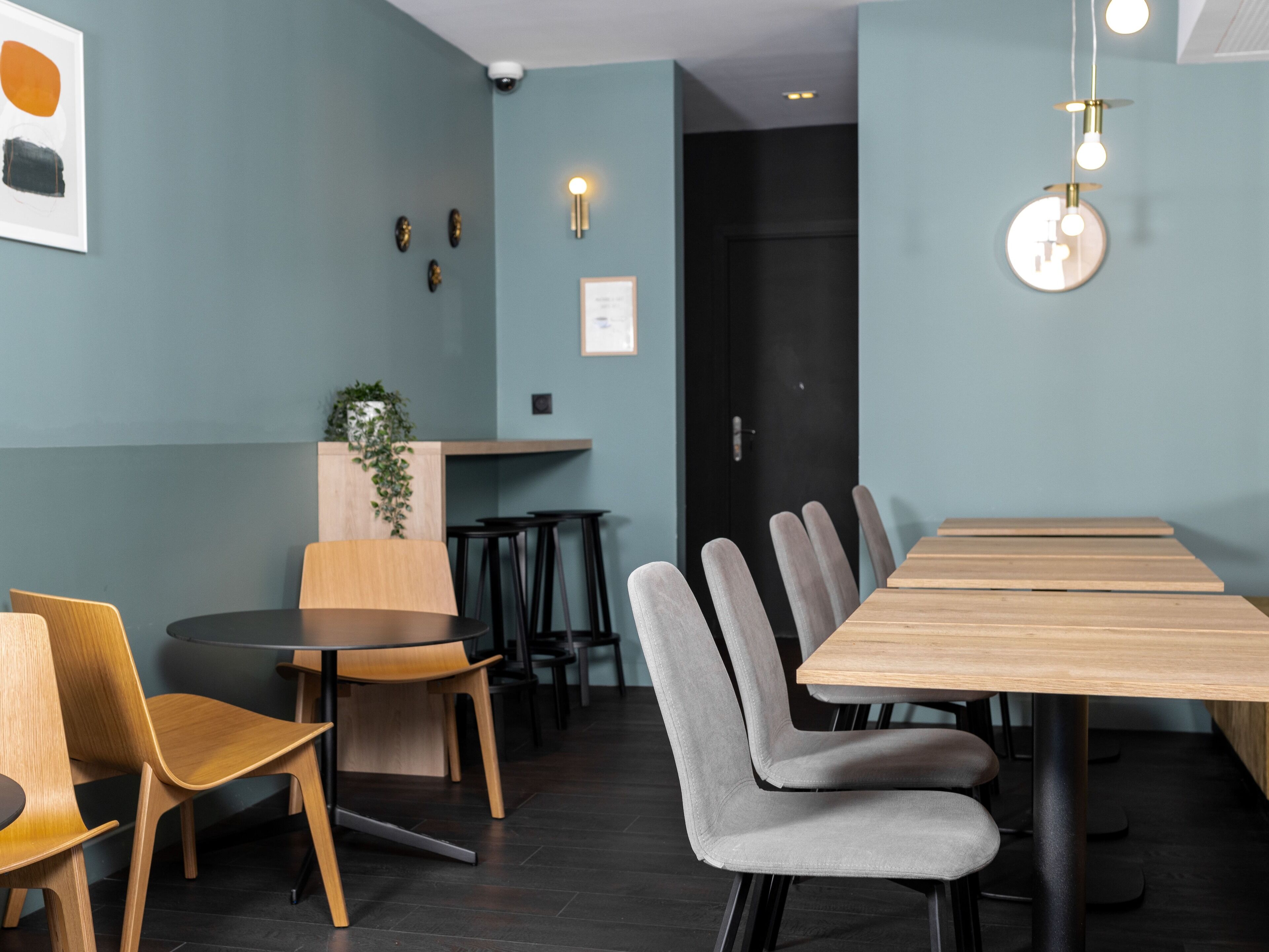 Una sala de conferencias moderna con una larga mesa de madera, sillas tapizadas en gris y una mesa redonda con sillas de madera.
