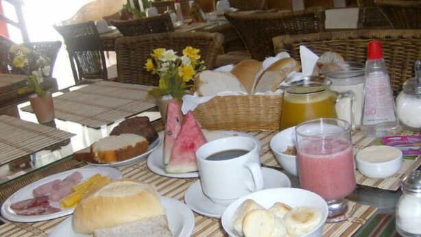 A breakfast table with bread, pastries, and a fruit bowl. - Quaraçá Pousada (Maceió)